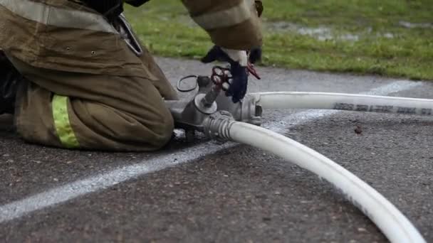 Nahaufnahme eines Feuerwehrmannes mit Schlauchspalter und Feuerwehrschläuchen, schraubt die Ventile ab — Stockvideo