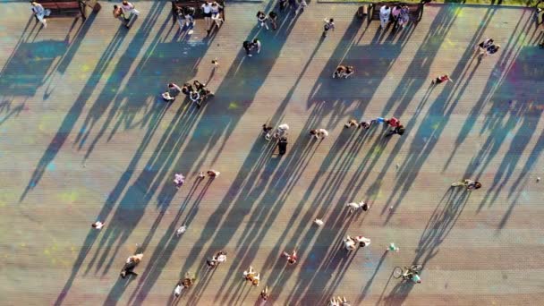 Uitzicht van quadrocopter naar mensen lopen rond op vierkante zomer bij zonsondergang — Stockvideo