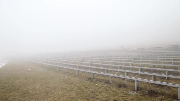Вид пустых скамеек перед сценой в очень сильном тумане осенью — стоковое видео