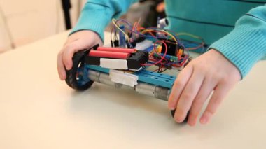 Robot teknolojisi ve Kök Eğitim sınıfı konsepti: Çocuk robotunu ayarlıyor. Çocuk okulunda bilgisayar laboratuvarında kodlama öğrenme programları
