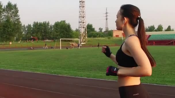 Kemerowo, Rosja - 11 lipca 2018: Zwolniony ruch. młoda kobieta sportowiec działa na bieżni w widok stadionu z tyłu — Wideo stockowe