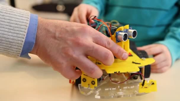 Robotics technology and STEM education class concept: Boy with teacher adjusts his robot. Programs for learning coding study in computer laboratory in school for kid — Stockvideo