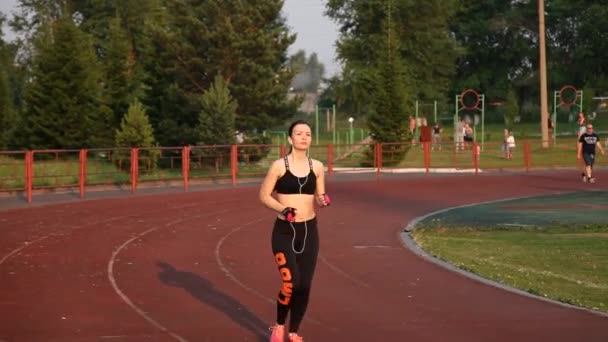 Kemerovo, Rusland - 11 juli 2018: jonge vrouwelijke atleet loopt in het stadion op loopband buiten — Stockvideo