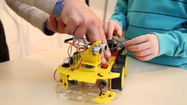 Robotics technology and STEM education class concept: Boy with teacher set up a robot to control with your smartphone — Stock Video