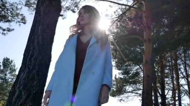 Bella giovane donna bionda in posa in cappotto nella foresta autunnale nel tempo soleggiato — Video Stock