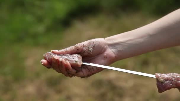 Closeup of female hand puts meat on skewer for barbecue — Stockvideo