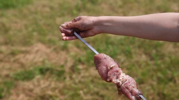 Крупный план женской руки кладет мясо на шампур для барбекю — стоковое видео