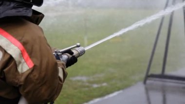 Close-up of firefighter extinguishing fire with fire hose
