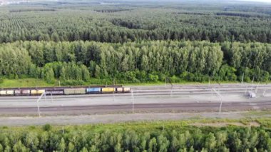 Aerial 4K fly over railway tracks with an empty cargo wagons in summer at sunset