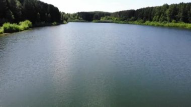 Aerial fly at high speed over water surface of a calm lake in summer Sunny day