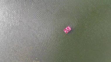 4k Aerial, güneşli bir günde, kırmızı yelkenli katamaranın üzerindeki insanların yukarıdan görünüşü.