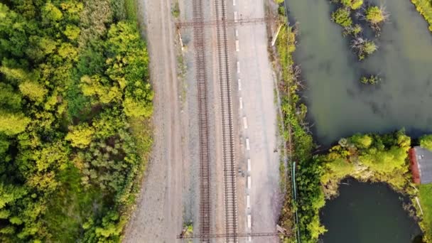 湖に沿って鉄道線路の空中ビュー。無人機からの鉄道のトップビュー — ストック動画
