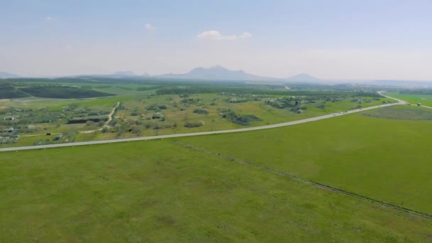 Vista aérea superior dos campos agrícolas ao longo da rodovia no fundo das montanhas — Vídeo de Stock