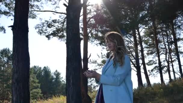 Belle jeune femme jette les cônes de conifères dans la forêt — Video