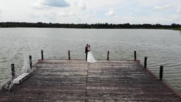 Aerial flight above of groom and bride hugging on wooden pier, flying over lake — Stock Video