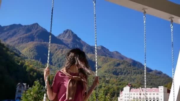 Jeune femme balançant sur balançoire sur fond pittoresque de paysages de montagne dans l'air frais — Video