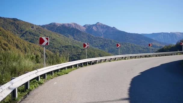 Turning asphalt road and signs in mountains. Beautiful landscape with mountain highway, blue sky and sun. Summer road. Travel background — Stok video