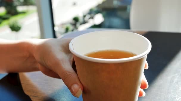 Mano femenina toma un vaso de té en la cafetería de la mesa — Vídeo de stock