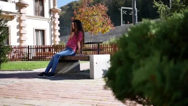 Young woman sitting on bench in summer day alone. outdoors — 图库视频影像