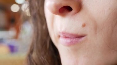 Tanınmayan genç bir kadın fast food restoranında patates kızartması yiyor. Bir eli patatesli, ağzı kapalı.