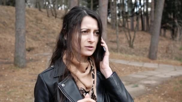 Portrait of unhappy young woman is talking on phone outdoors angry — Stock Video