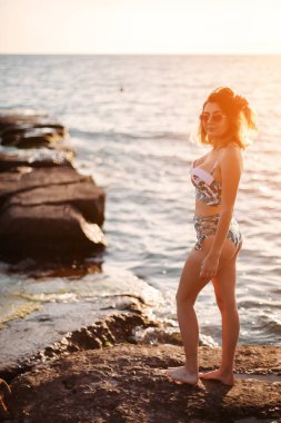 Bikinili ve plajda gözlüklü genç bir kadın. 