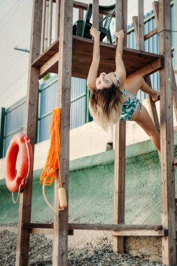 sexy young beautiful smiling woman in bikini funny makes faces and poses on the beach near the rescue tower
