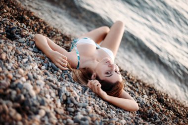 Fashion shot of a beautiful sexy girl in bikini lying on beach