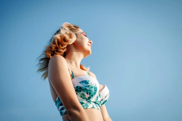 Mujer joven divertida en bikini y gafas de sol en la playa al atardecer . — Foto de Stock