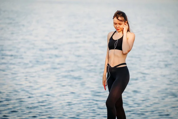 Fiatal sportos nő a tengerparton futó hallgató-hoz zene, hea — Stock Fotó