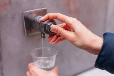 Yessentuki, Stavropol Territory / Russia - February 26, 2019: Drinking gallery of mineral spring Essentuki 17. indoors. close - up of young woman gaining glass of mineral water from tap