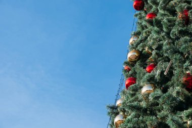 Açık havada gökyüzüne karşı güzel dekore edilmiş Noel ağacının yakın çekimi. Tatil arkaplanı