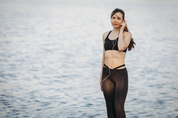 Joven atlética mujer en corredor de la playa escuchando música con hea — Foto de Stock