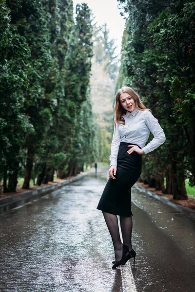 Young business woman in skirt posing outdoors in the rain