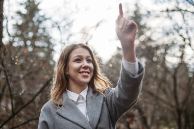 Sokakta paltolu genç bir kadın parmağını kaldırıyor.