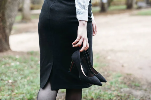 Primo piano di giovane donna che tiene scarpe nere all'aperto — Foto Stock