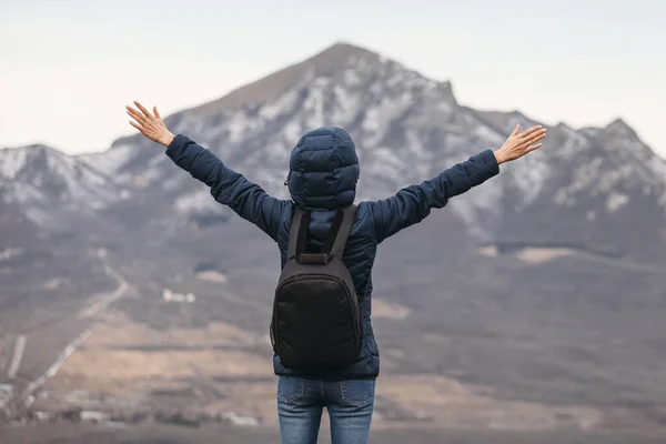 hiker on background mountains with arms raised in air