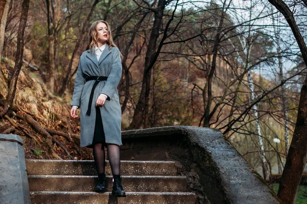 Beautiful girl in a coat walks down stairs in autumn Park. copy — Stock Photo, Image