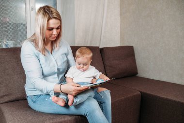 Çocuk dünyayı öğreniyor. Anne kucağında küçük bir çocukla peri masallarıyla kitap okuyor.