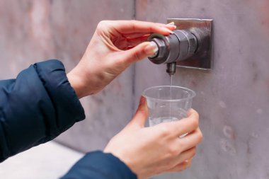 Yessentuki, Stavropol Territory / Russia - February 26, 2019: Drinking gallery of mineral spring Essentuki 17. indoors. close - up of young woman gaining glass of mineral water from tap