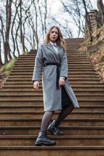 가을에 공원의 계단에서 회색 코트를 입은 젊은 소녀 — 스톡 사진