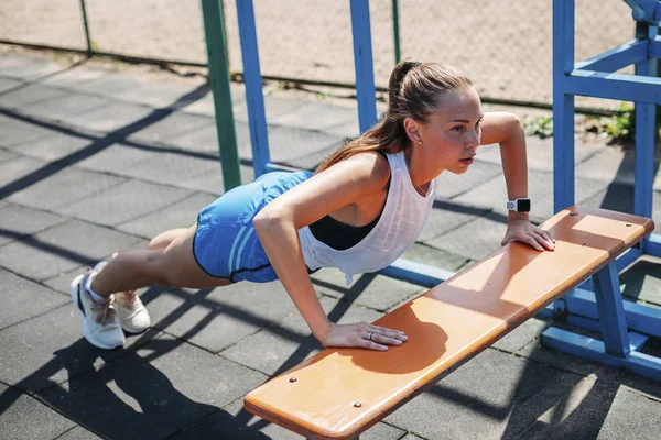 Sportive jeune femme sexy faire push-UPS à partir du banc sur le terrain de sport — Photo