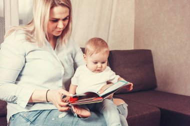 Ailedeki tek çocuk. Anne kucağında küçük bir çocukla peri masallı bir kitap okuyor.