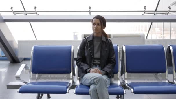 Belle jeune femme à l'aéroport est assis sur la chaise attendant l'avion — Video