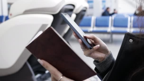 Junge Frau am Flughafen kauft Flugticket per Telefon, gibt Passdaten ein, um Flugticket zu kaufen — Stockvideo