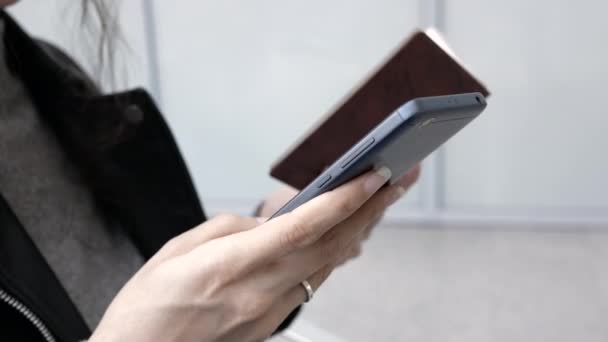 Gros plan de la jeune femme à l'aéroport achetant un billet d'avion par téléphone, elle entre les données de passeport pour acheter un billet — Video