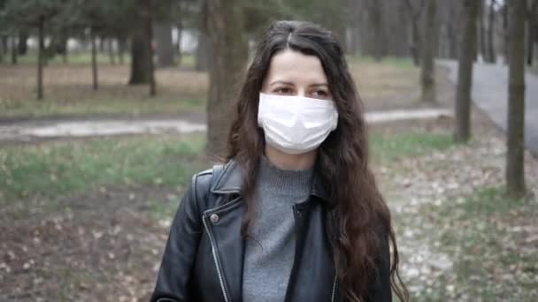 Vrouw met masker en kijkend naar de camera in de stad. Gezondheidszorg en medisch concept — Stockvideo