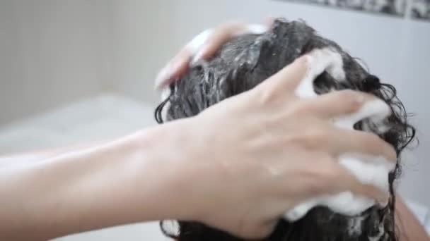 Een vrouw die haar haar wast met shampoo. Haarverzorging, schoonheidsconcept — Stockvideo