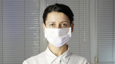 Eldivenli genç kadın doktor, tıbbi maske takıyor..