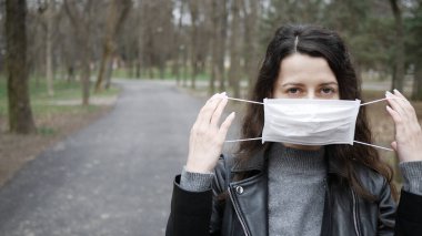 Genç kadın salgının ortasında yüzüne koruyucu bir maske takıyor. kopyalama alanı. Model